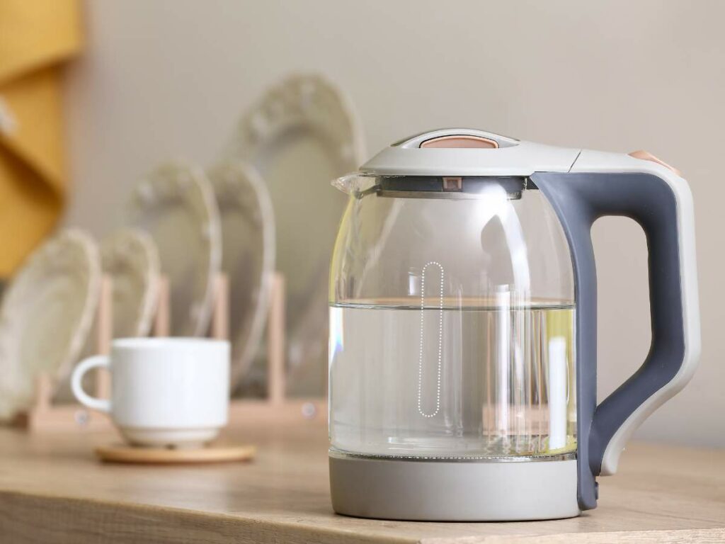 Electric glass kettle with water on a kitchen countertop.