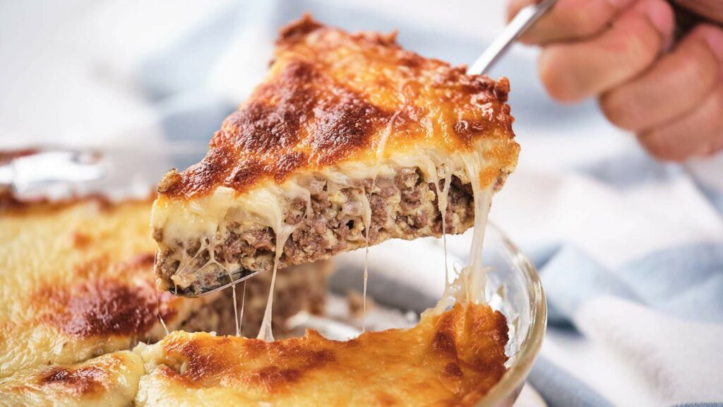 A slice of cheeseburger pie being lifted up from the dish.