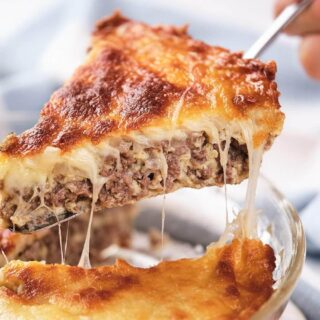 A slice of cheeseburger pie being lifted, showing layers of meat and melted cheese.