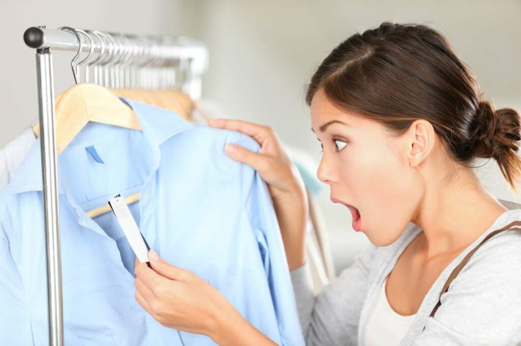 Woman surprised by price tag while shopping for clothes.