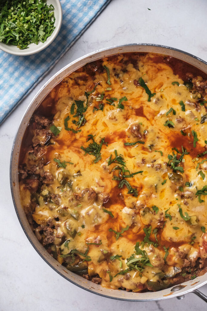 A skillet of cheesy ground beef casserole topped with melted cheese.