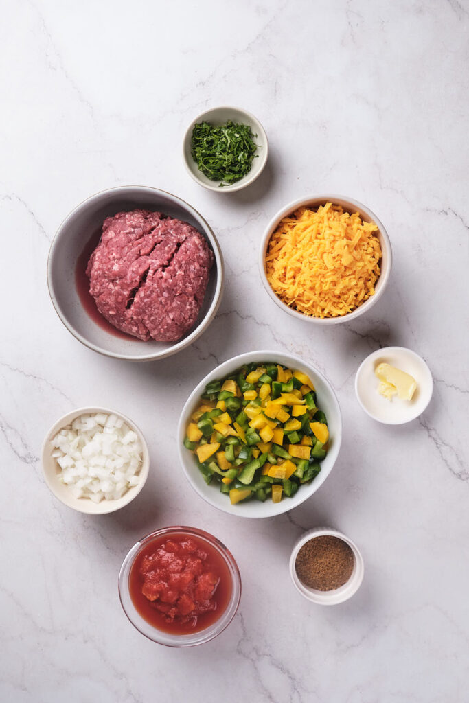 Various ingredients for taco skillet arranged on a marble surface.