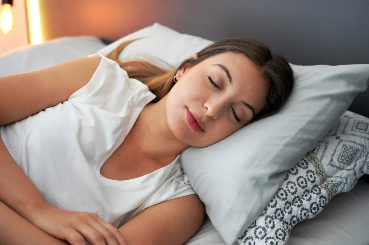 A woman sleeping peacefully on a pillow in a softly lit room.