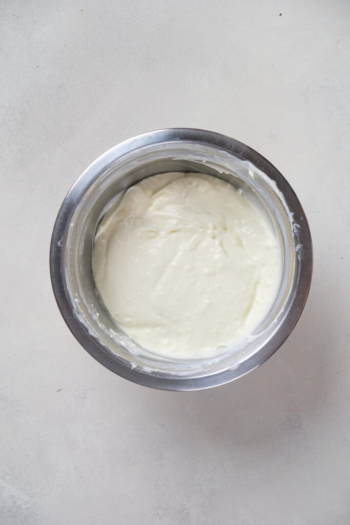 A bowl containing white cream placed on a light-colored surface.