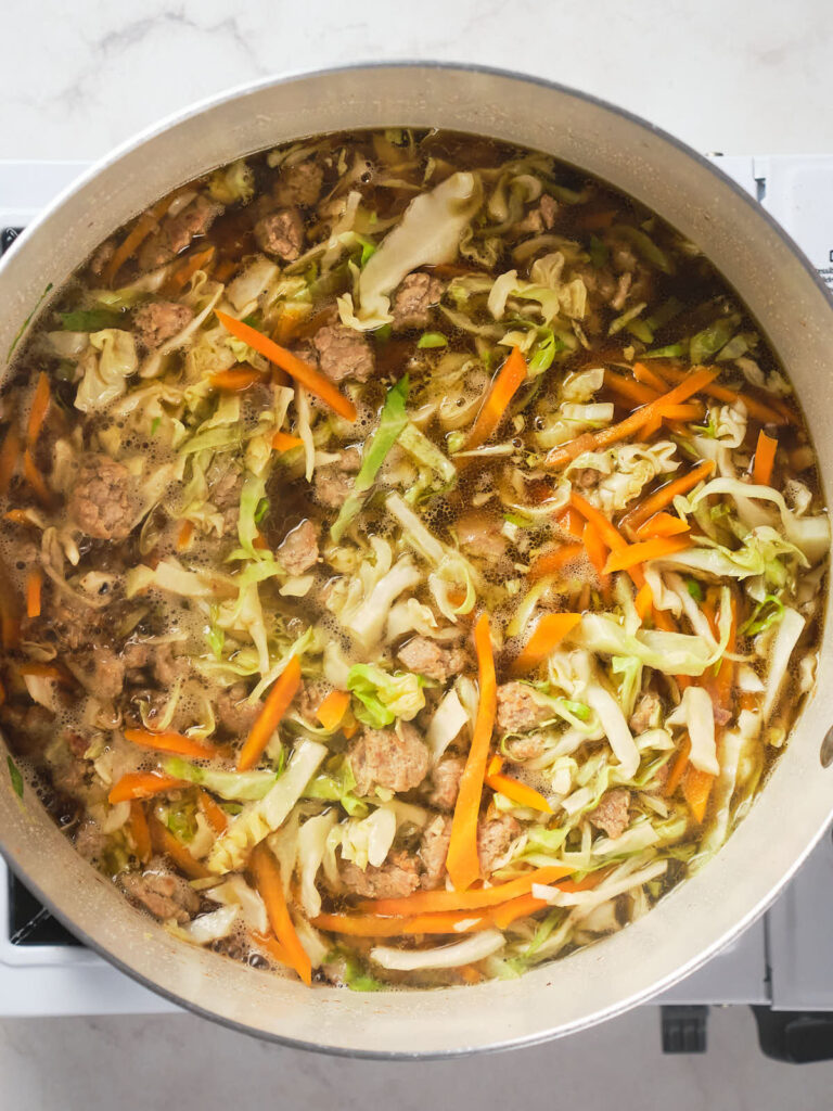 A large pot of egg roll soup cooking on a stove.