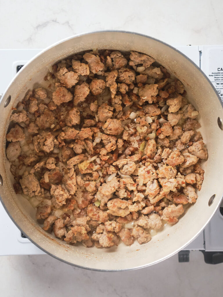 A pot containing browned and crumbled meat on a stovetop.