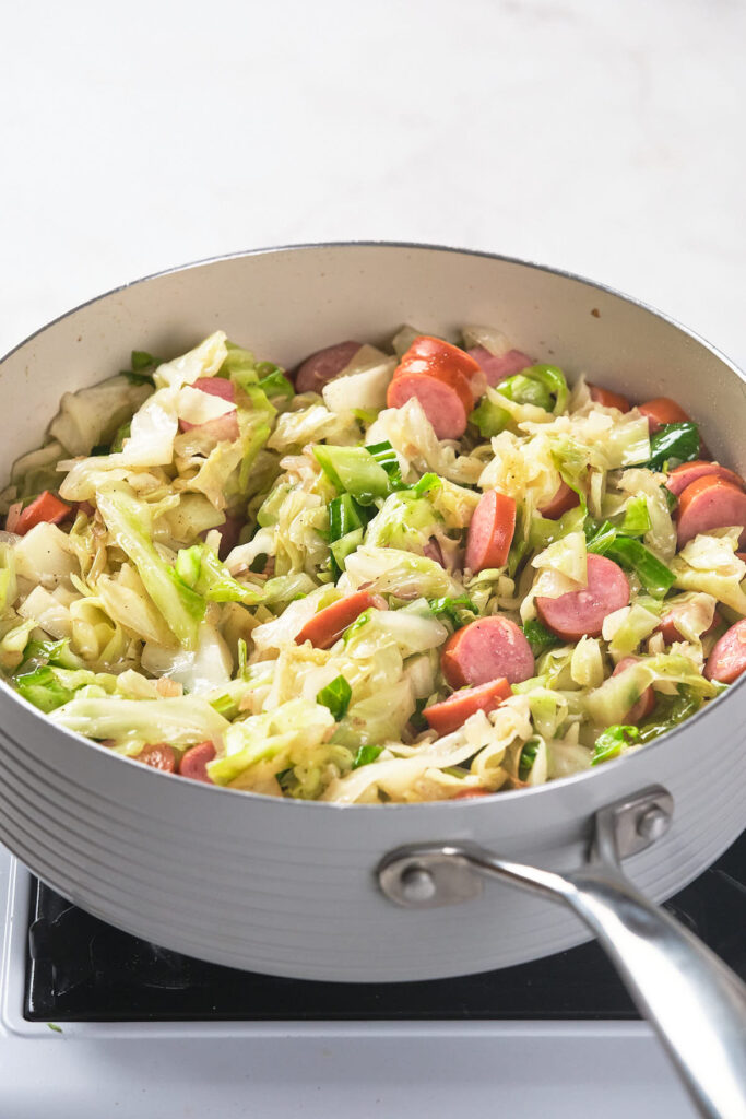 A skillet filled with fried cabbage and sausage.