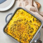 A casserole dish containing a baked dish with a golden crust, seasoned with herbs.