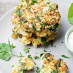 A white plate with a stack of cabbage fritters garnished with parsley.