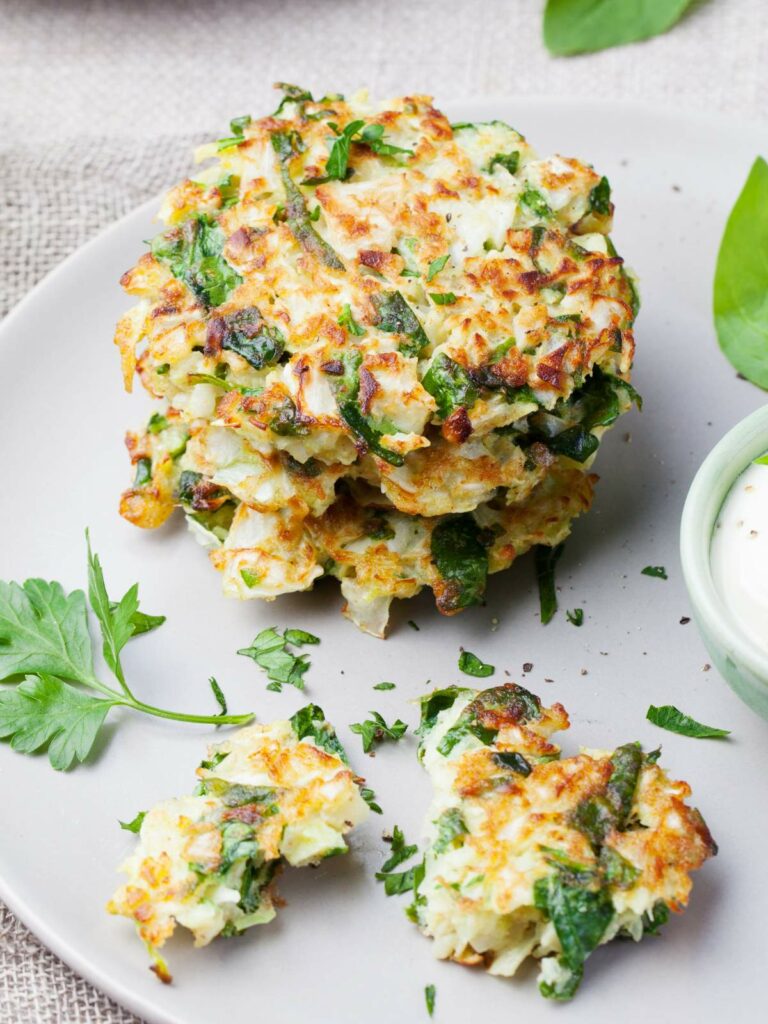 A white plate with a stack of vegetable fritters garnished.