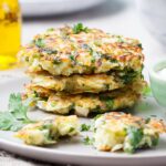 A stack of vegetable fritters garnished with parsley on a gray plate.