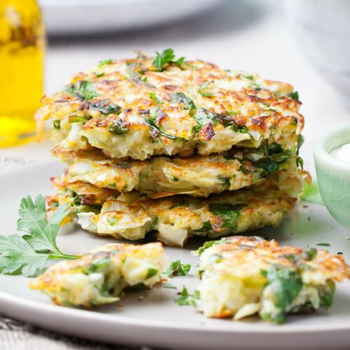 A stack of vegetable fritters garnished with parsley on a gray plate.