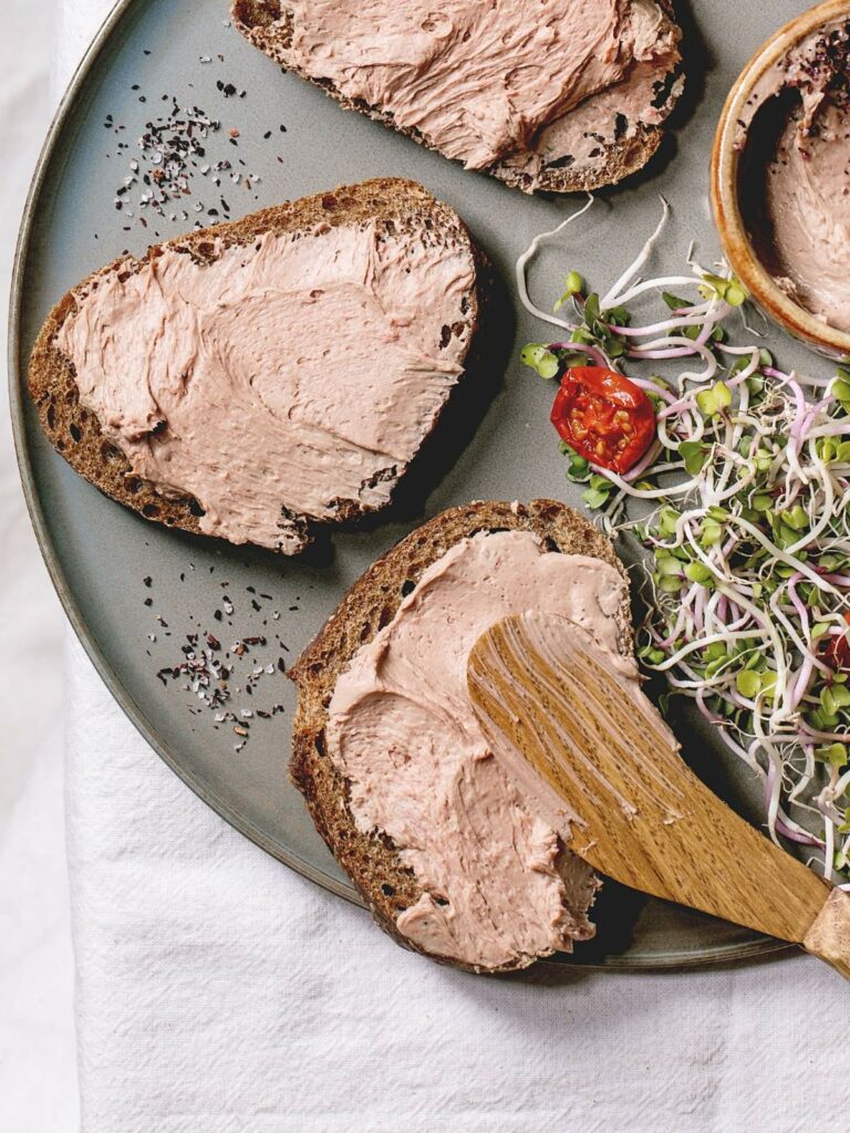 A plate with three slices of bread topped with a pink spread.