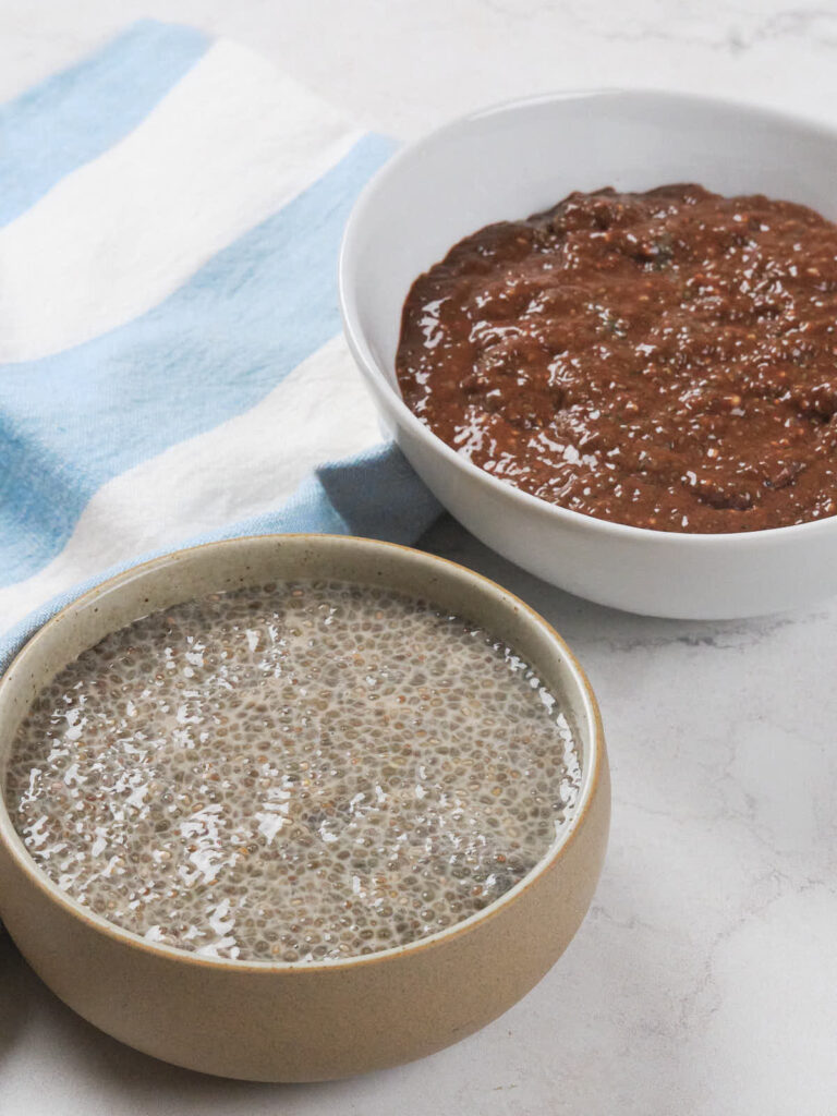 Two bowls of chia pudding on a marble surface.