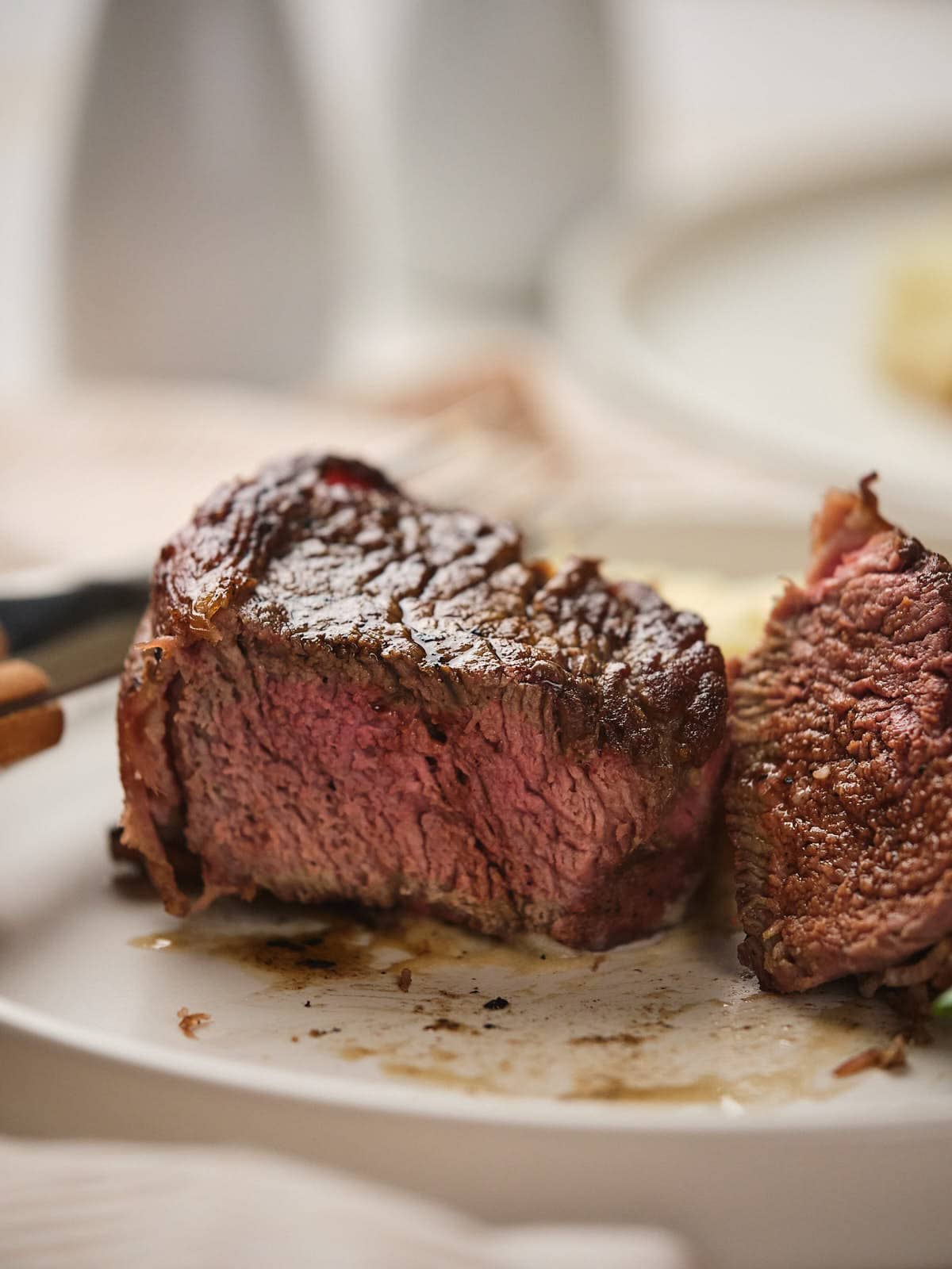 Bacon-wrapped beef tenderloin partially cut to reveal its pink interior.