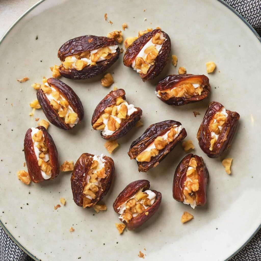 Plate of halved dates filled with goat cheese and chopped nuts.