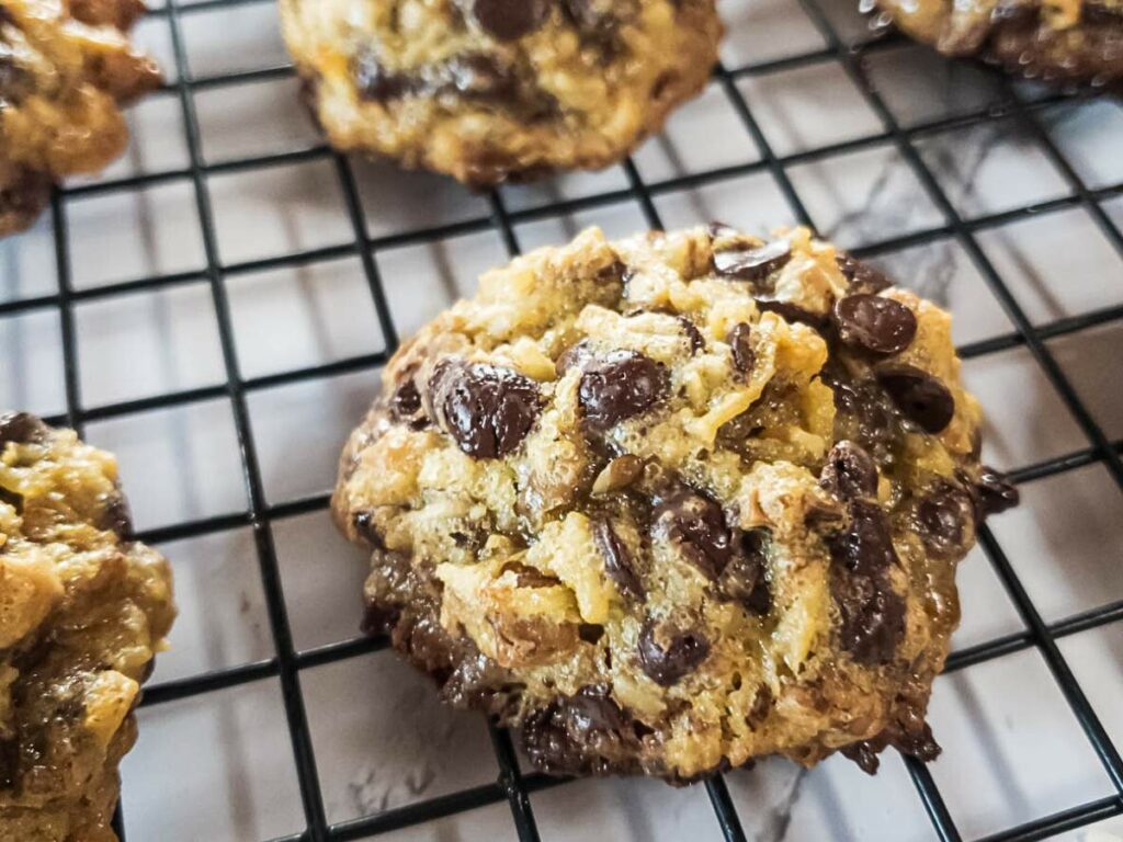 Keto magic cookies on a black wire cooling rack, surrounded by other cookies, with a marble countertop underneath.