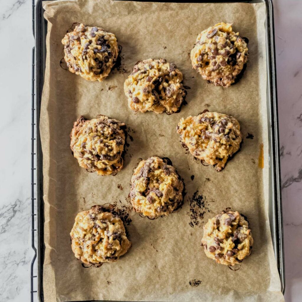 Eight chocolate chip cookies on a parchment-lined baking tray.