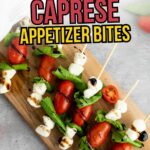 Wooden board with skewers of cherry tomatoes, mozzarella balls, and basil leaves, drizzled with balsamic glaze.
