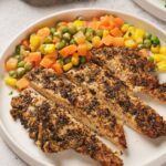 Pan seared chicken breast on a plate with mixed vegetables including corn, peas, carrots, and beans.