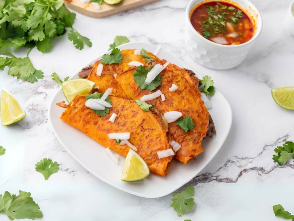Two quesabirria tacos garnished with chopped onions and cilantro are served on a white plate.