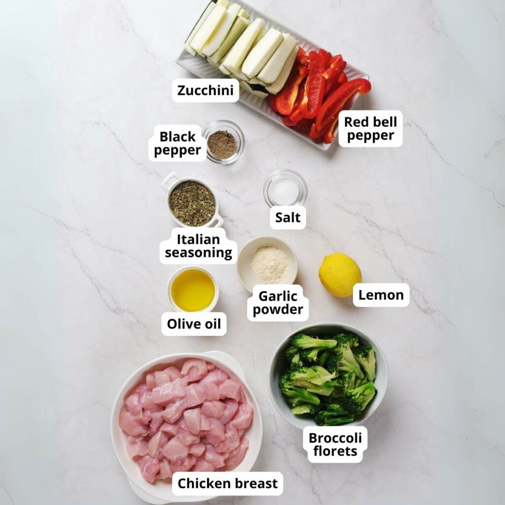 Ingredients for sheet pan chicken with vegetables on a light colored surface.