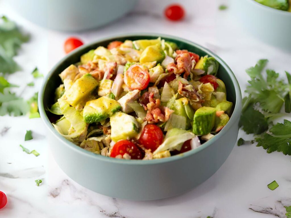 A bowl of chopped chicken salad on a white surface.