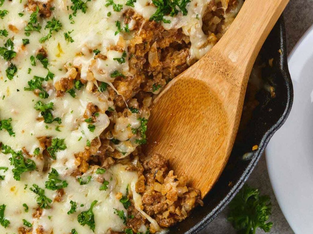 Italian ground beef skillet topped with chopped parsley from a black skillet.