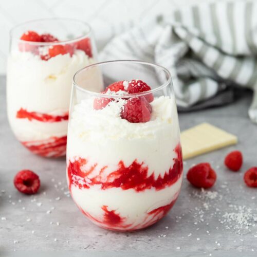 Two glasses filled with white chocolate raspberry mousse, topped with fresh raspberries.