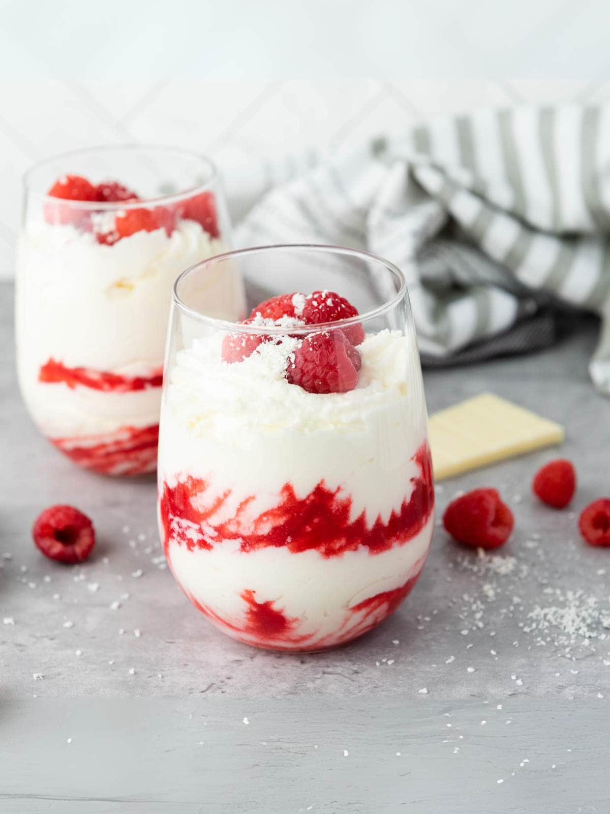 Two glasses filled with white chocolate raspberry mousse, topped with fresh raspberries.