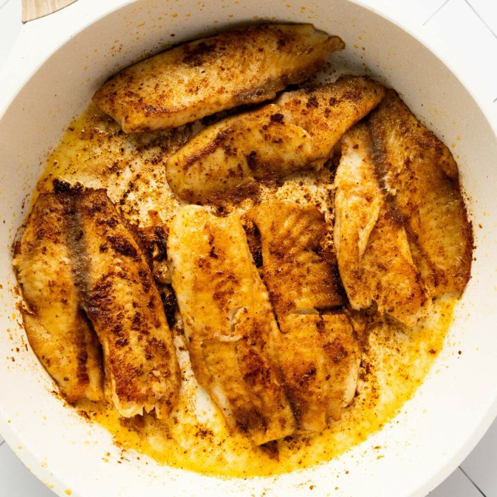 Several seasoned fish fillets are being cooked.