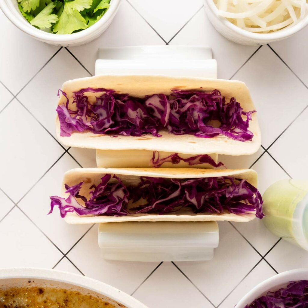 Two soft tacos filled with shredded red cabbage.