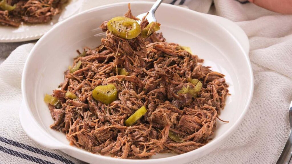 A white bowl filled with italian beef and sliced peppers.