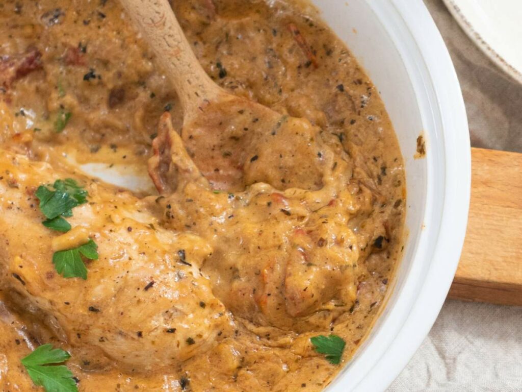 Chicken in a creamy, seasoned sauce garnished with parsley.