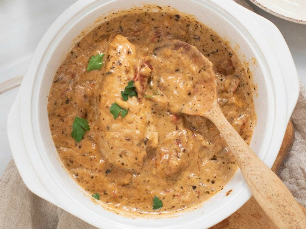 A seasoned chicken in a thick sauce, garnished with parsley.