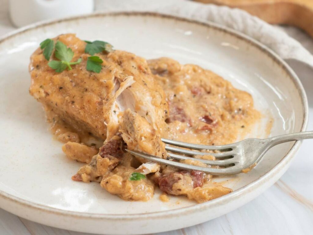 A cooked chicken breast topped with a creamy sauce.