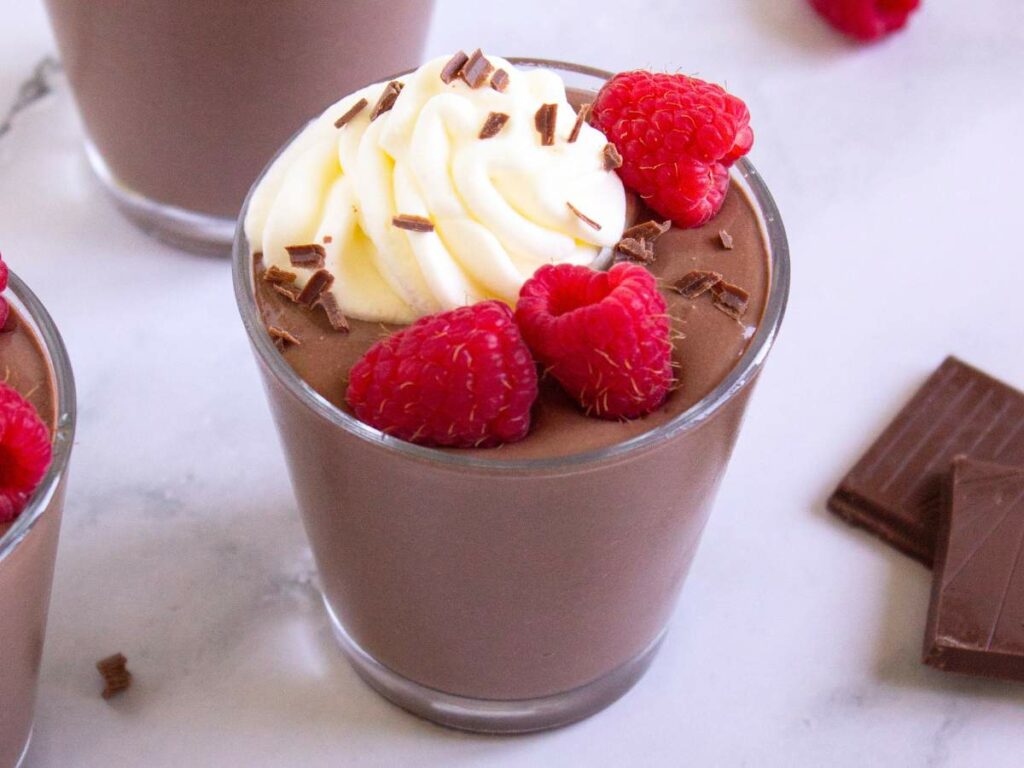 A glass of protein pudding topped with whipped cream, chocolate shavings.