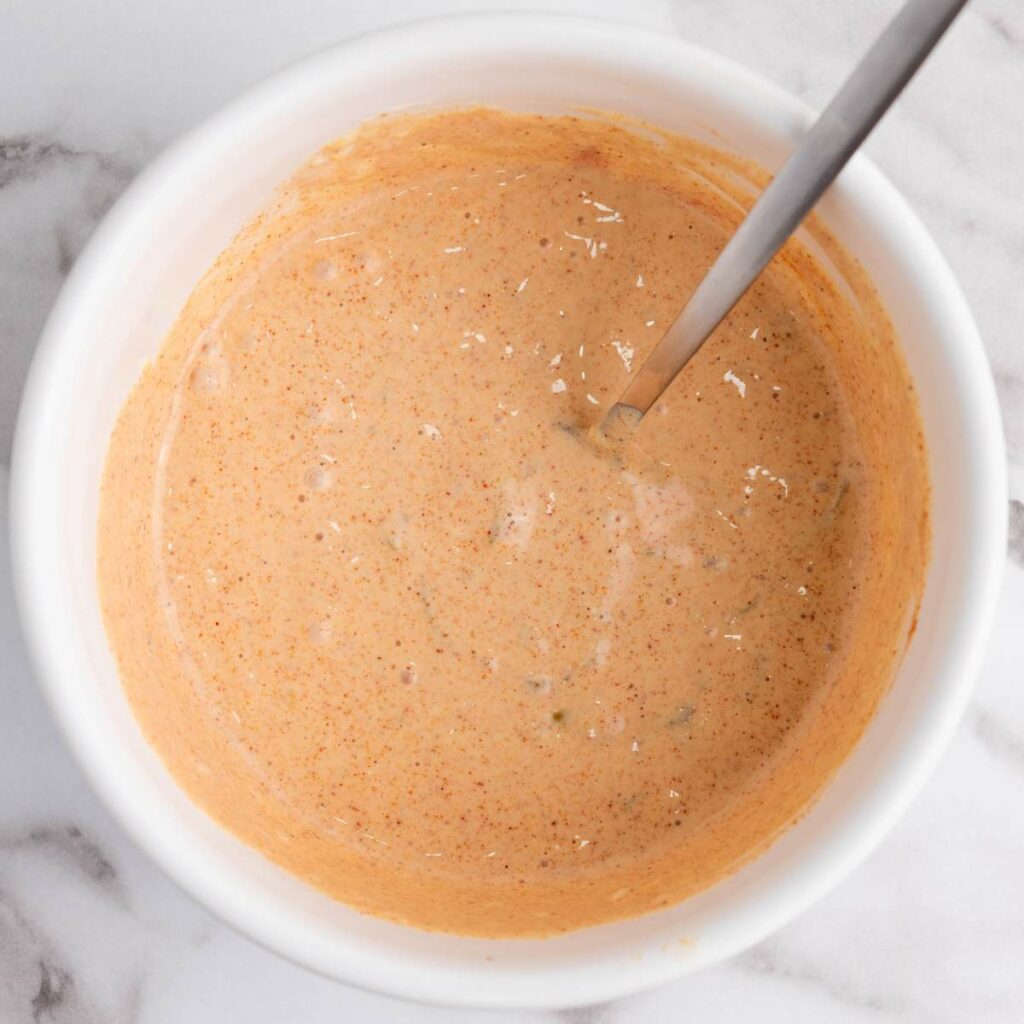 A white bowl containing a creamy, orange-colored sauce.