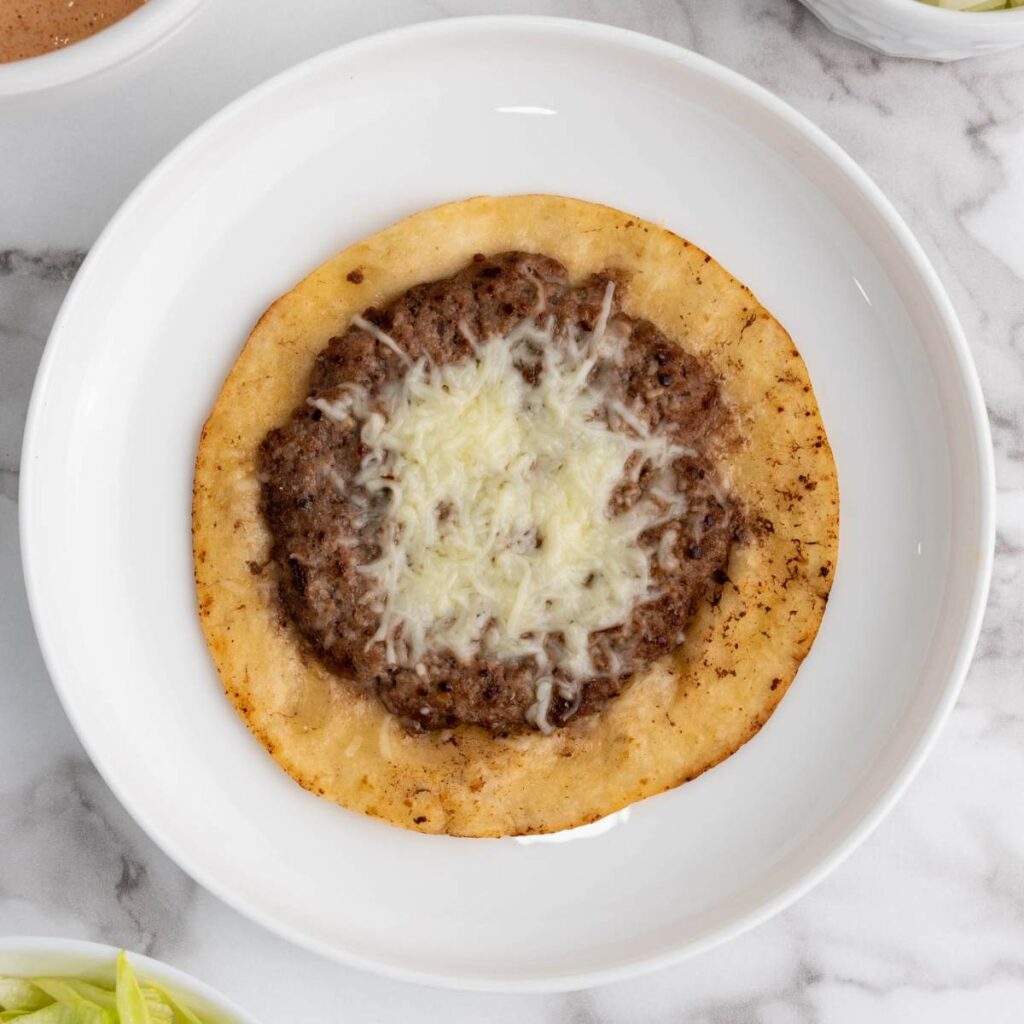 A tostada topped with ground beef and melted cheese.