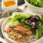 A plate with stuffed chicken breast topped with herbs.