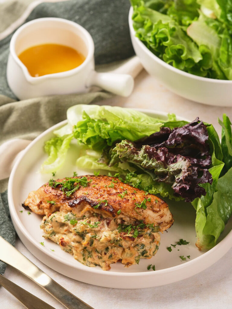 A plate with stuffed chicken breast topped with herbs.