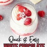 A glass of white chocolate raspberry mousse topped with raspberries and grated white chocolate.