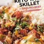 A plate of keto taco skillet with ground beef, melted cheese, vegetables, and fresh herbs served alongside white rice.