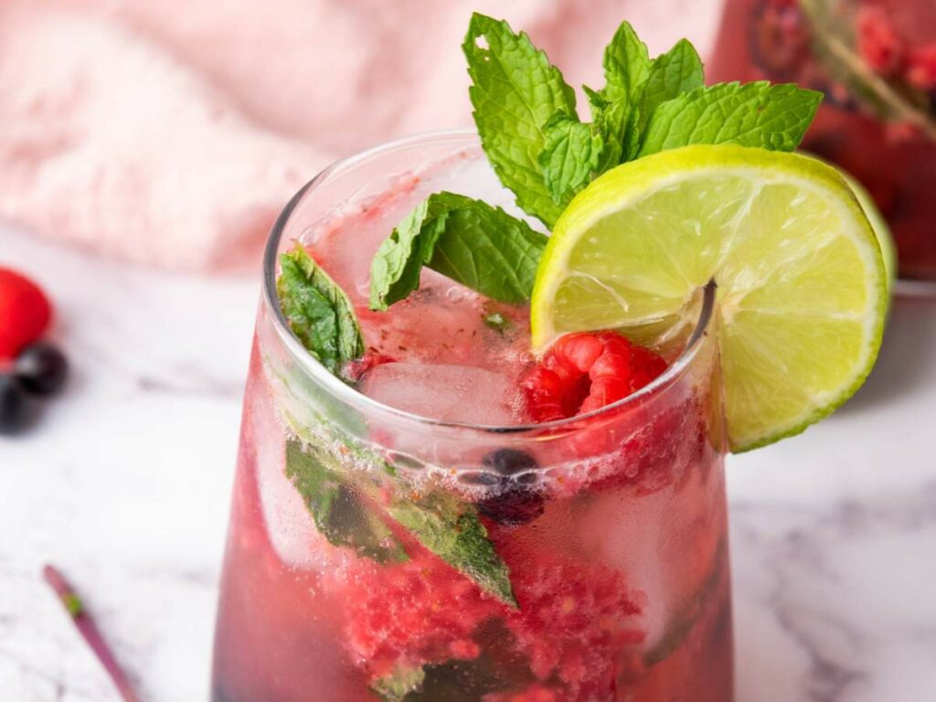 Close-up look of sparkling blueberry mocktail with ice, fresh mint and lime.