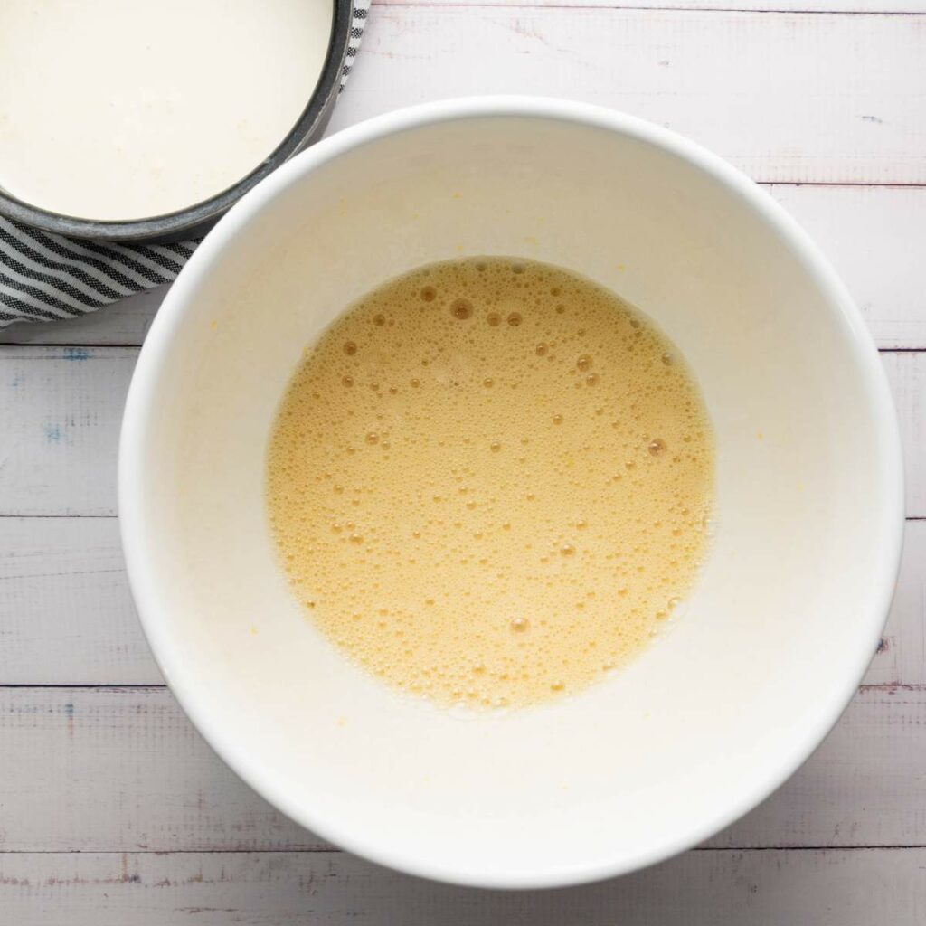 A white bowl containing a frothy, pale yellow liquid mixture.