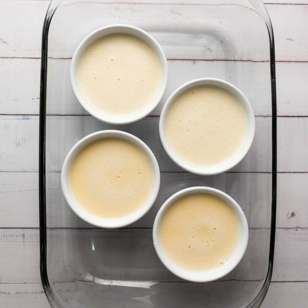 Four white ramekins filled with a light yellow custard mixture.