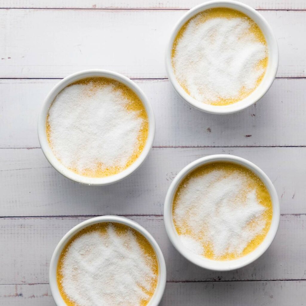 Four white ramekins filled with a yellow custard-like mixture.