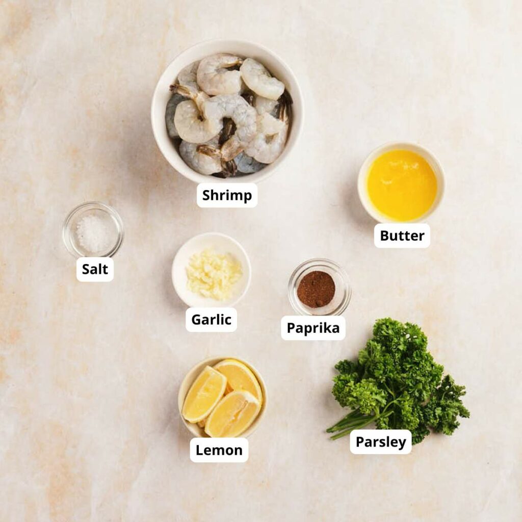 Top-down view of garlic butter shrimp labeled ingredients on a light surface.