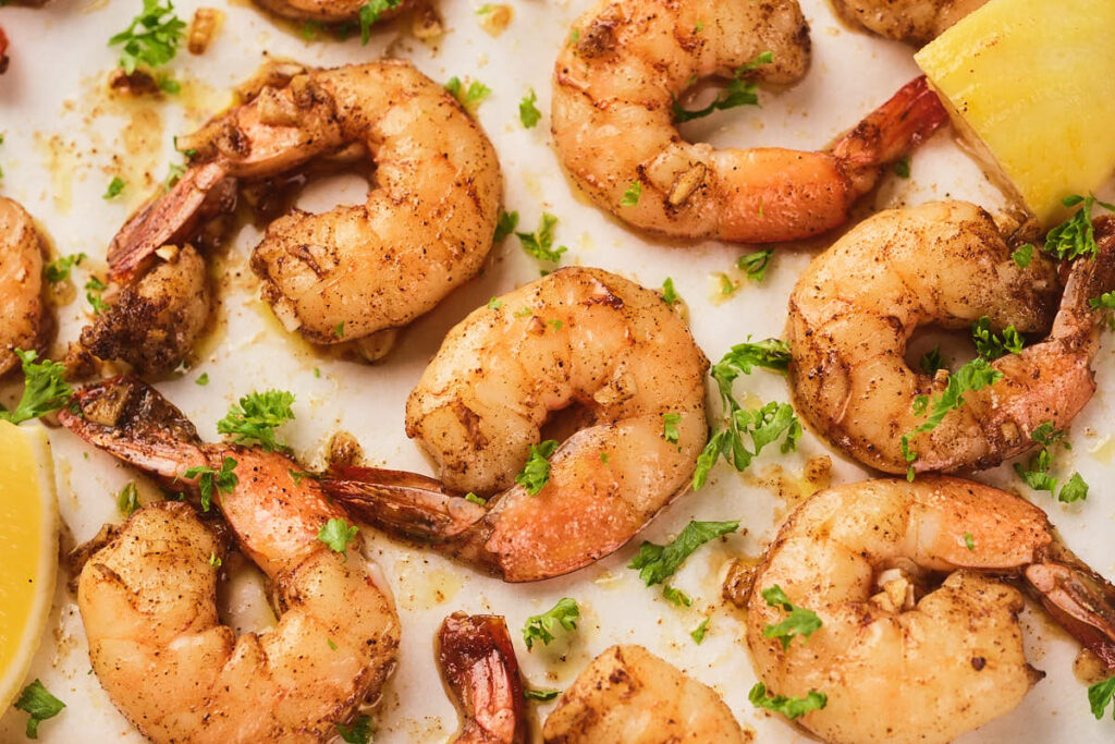 Cooked garlic butter shrimp seasoned with spices and garnished with chopped parsley.