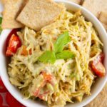 A bowl of healthy chicken salad with sliced cherry tomatoes, topped with cilantro.